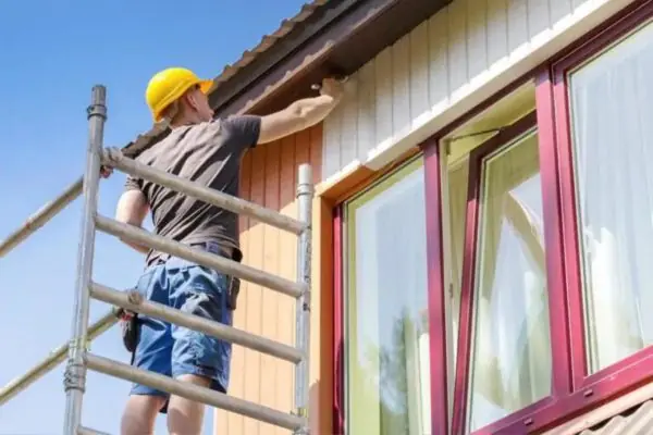 a contractor painting the exterior of a house of a house using acrylic paint