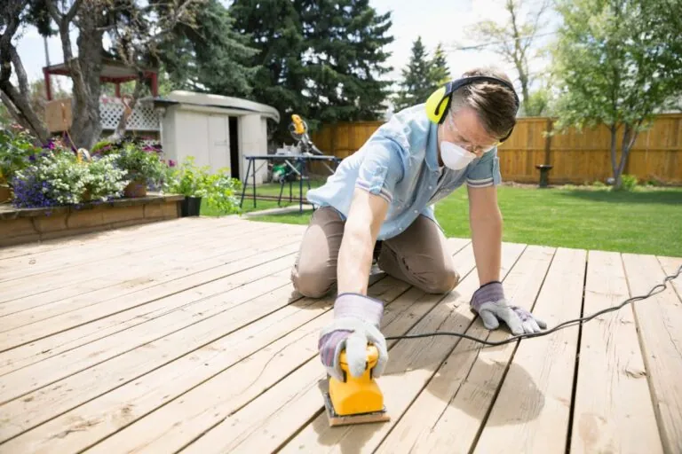 man sanding backyard deck