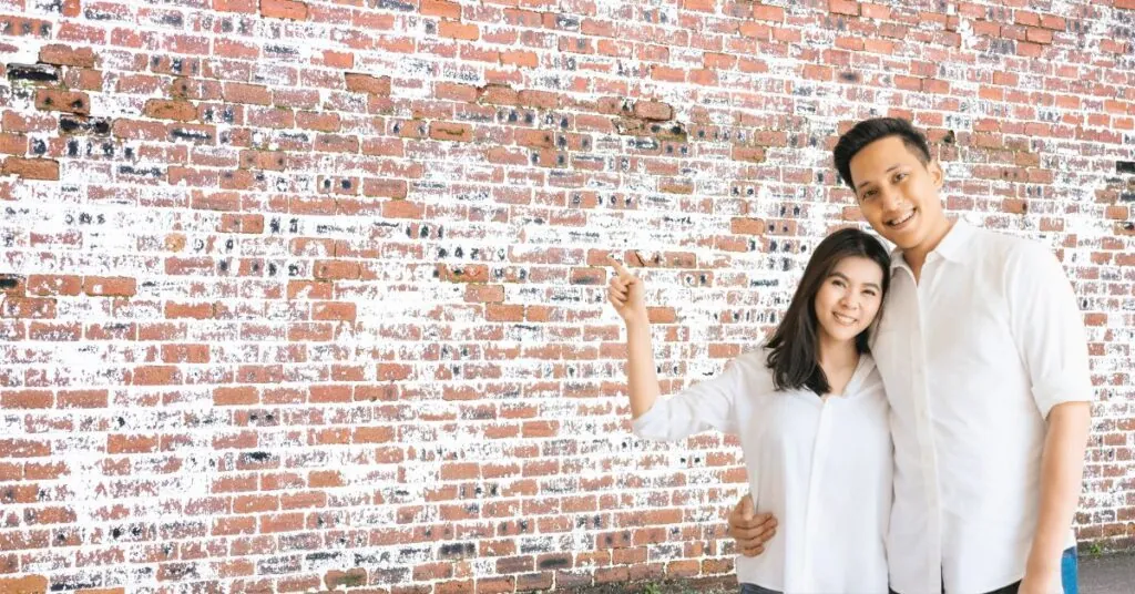 happy couple showing white wash brick exterior